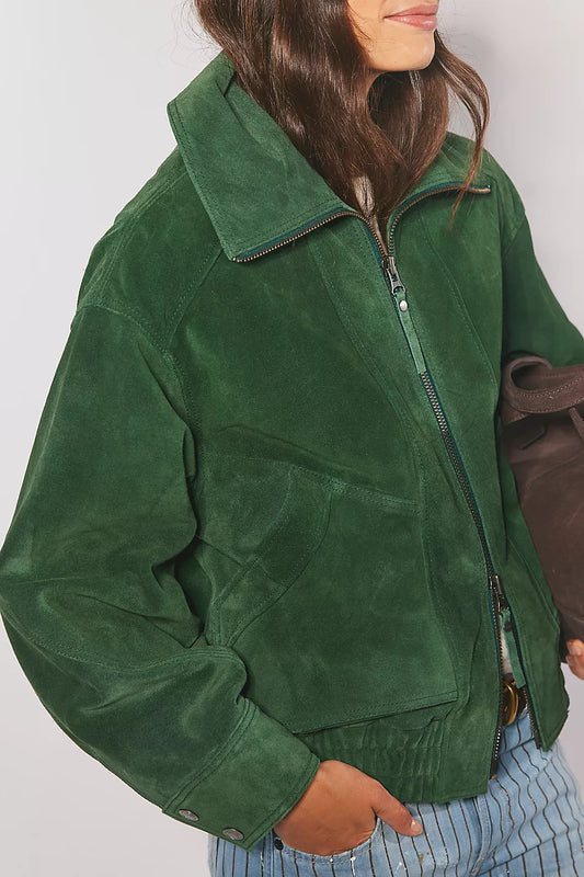 Green suede jacket with striped pants and a brown bag, shown from neck to hip.