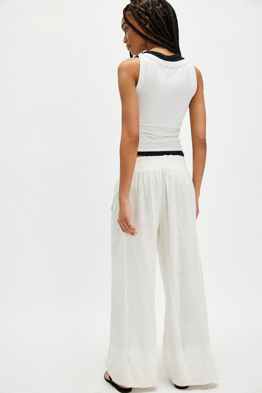 Woman wearing a white sleeveless top and ivory linen pull-on pants, viewed from the back.