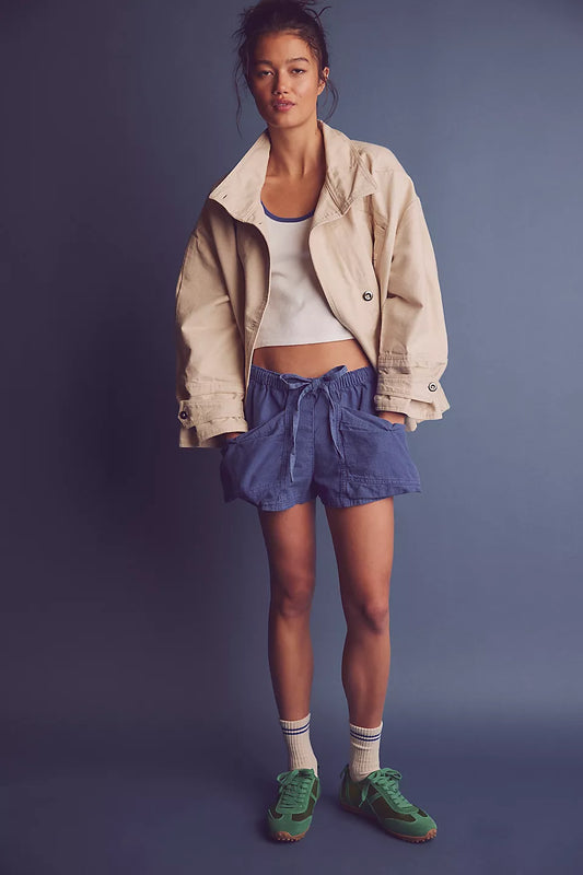 Woman wearing a beige jacket, white top, blue shorts