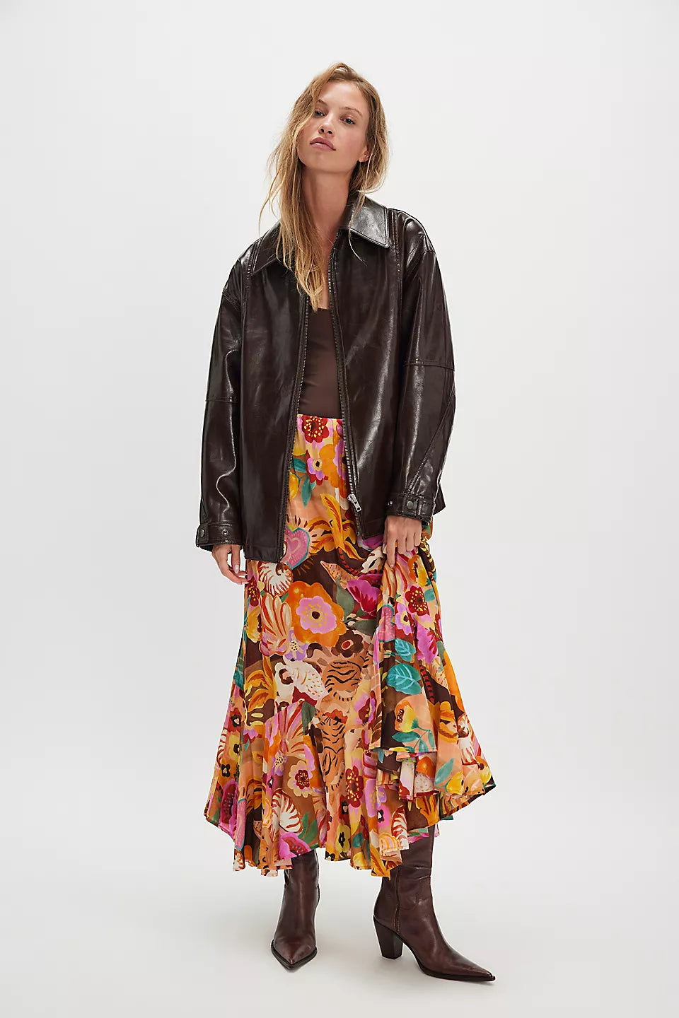 Woman wears caramel-colored maxi skirt with flowing fabric, suitable for casual or semi-formal occasions, set against white background.