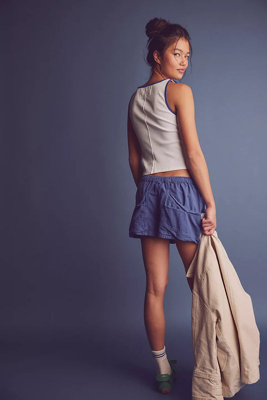 Woman wearing a beige jacket, white top, blue shorts